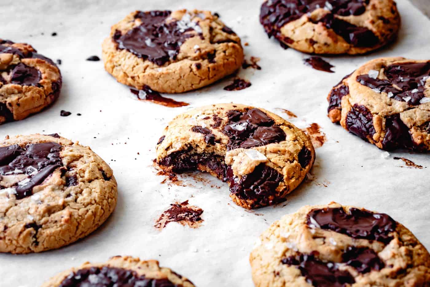 paleo grain-free chocolate chip cookies on a cookie sheet with a bite taken out