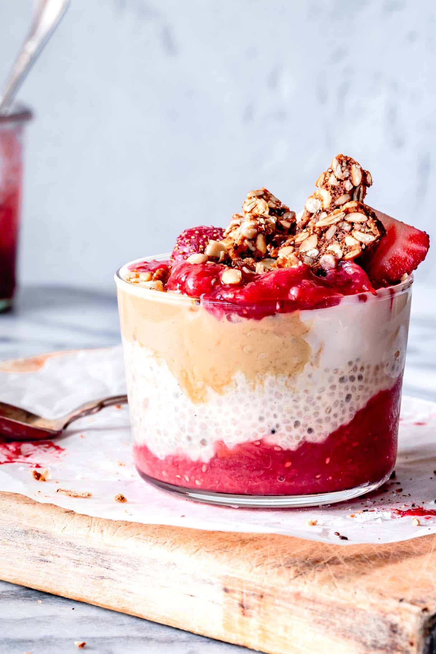 chia pudding layered with red jam and tahini topped with chopped granola bar