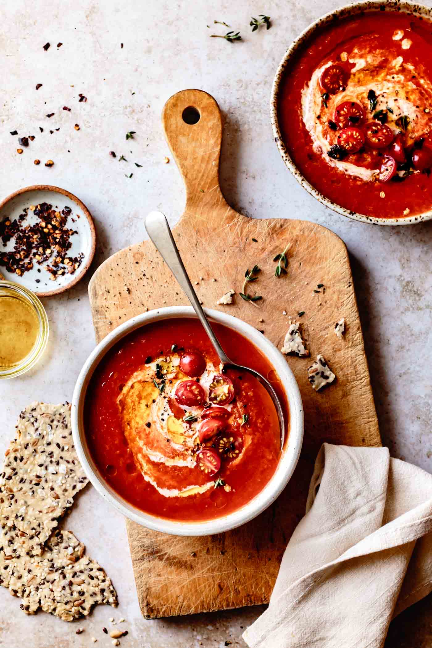 two bowls of creamy vegan roasted tomato soup with crackers