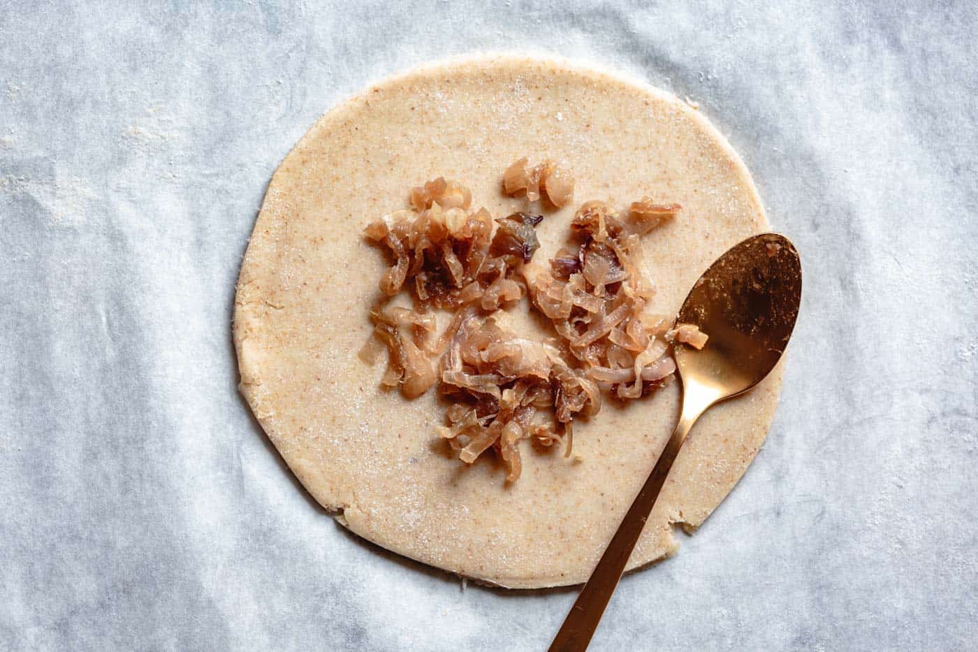 spreading shallots on dough round for fig galette recipe