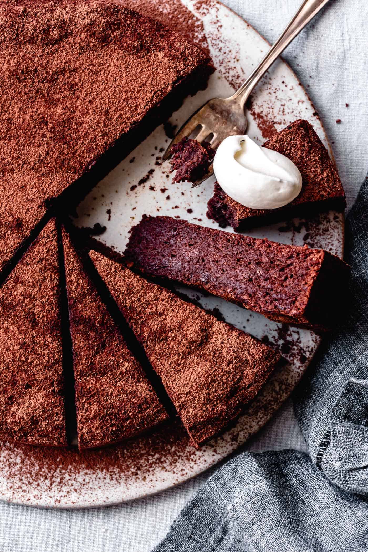 almond flour chocolate cake recipe, sliced on a serving board with whipped cream