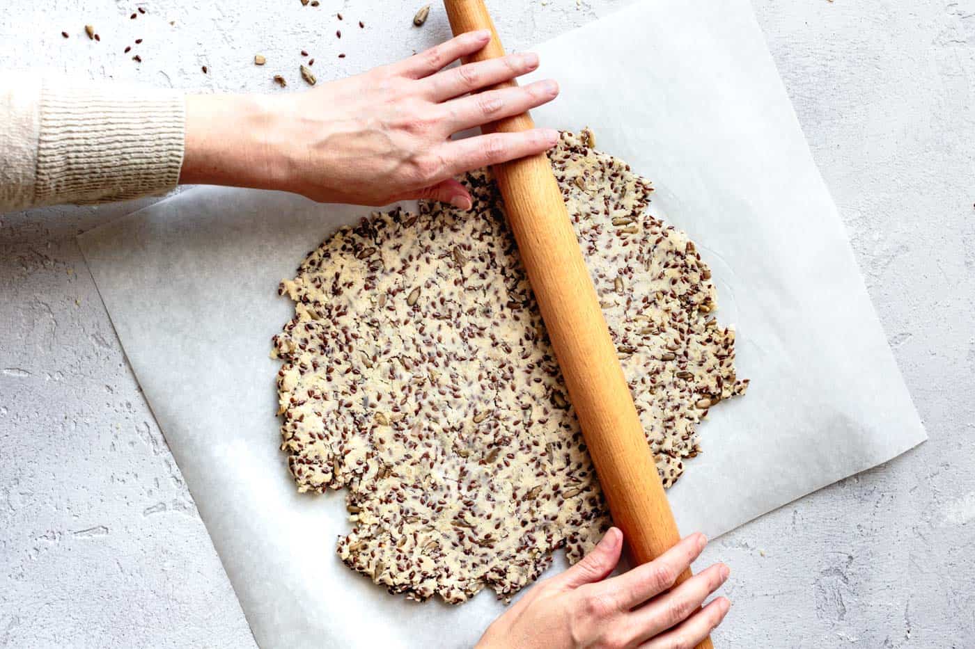 rolling the gluten-free crackers on a piece of parchment paper