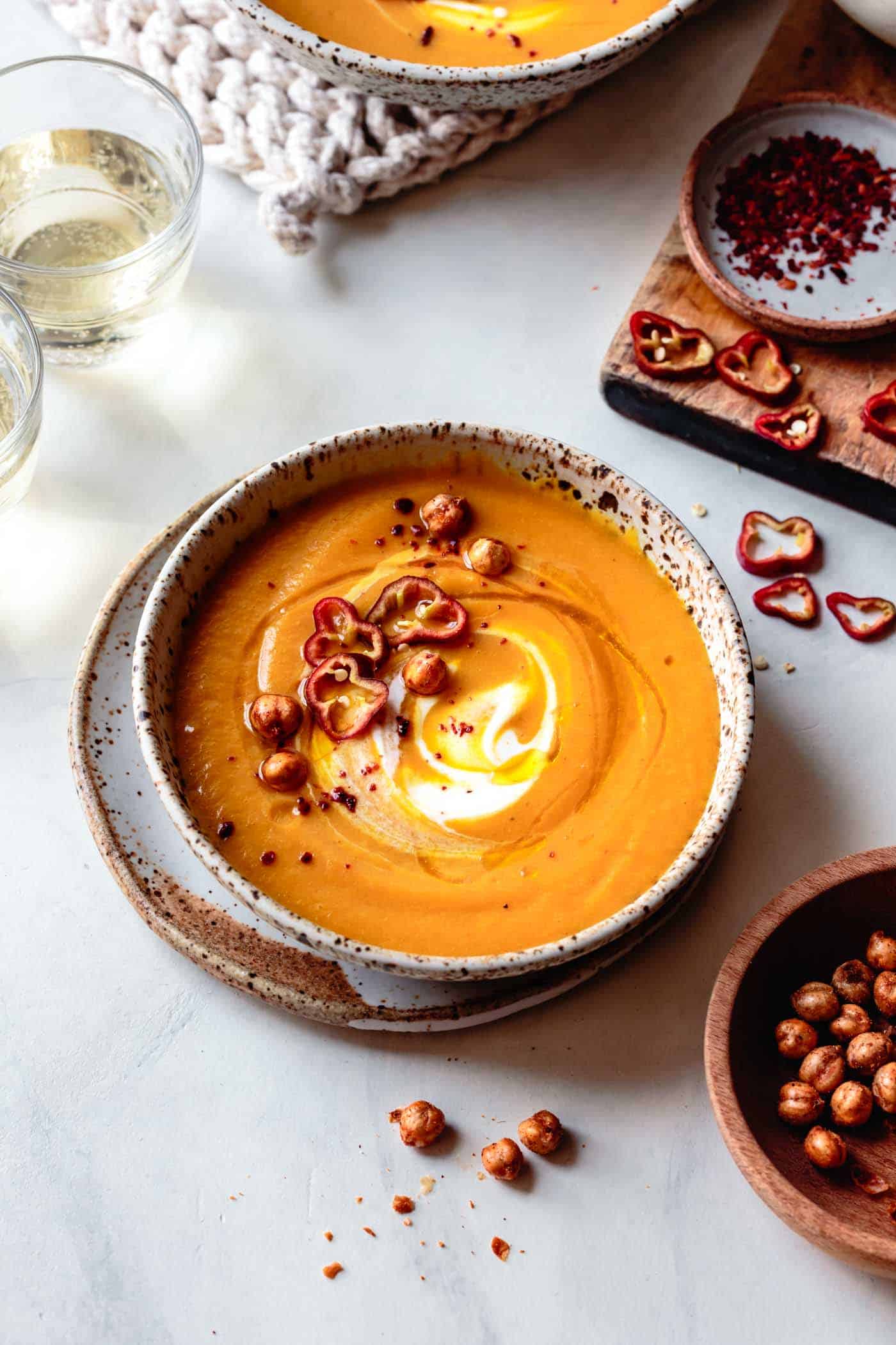 bowl of carrot ginger curry soup surrounded by ingredients