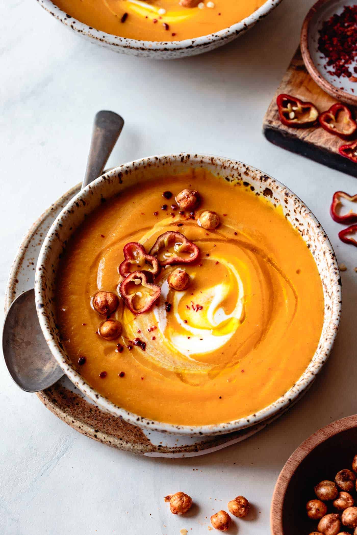 bowl of carrot coconut curry soup topped with a swirl of yogurt and crispy chickpeas