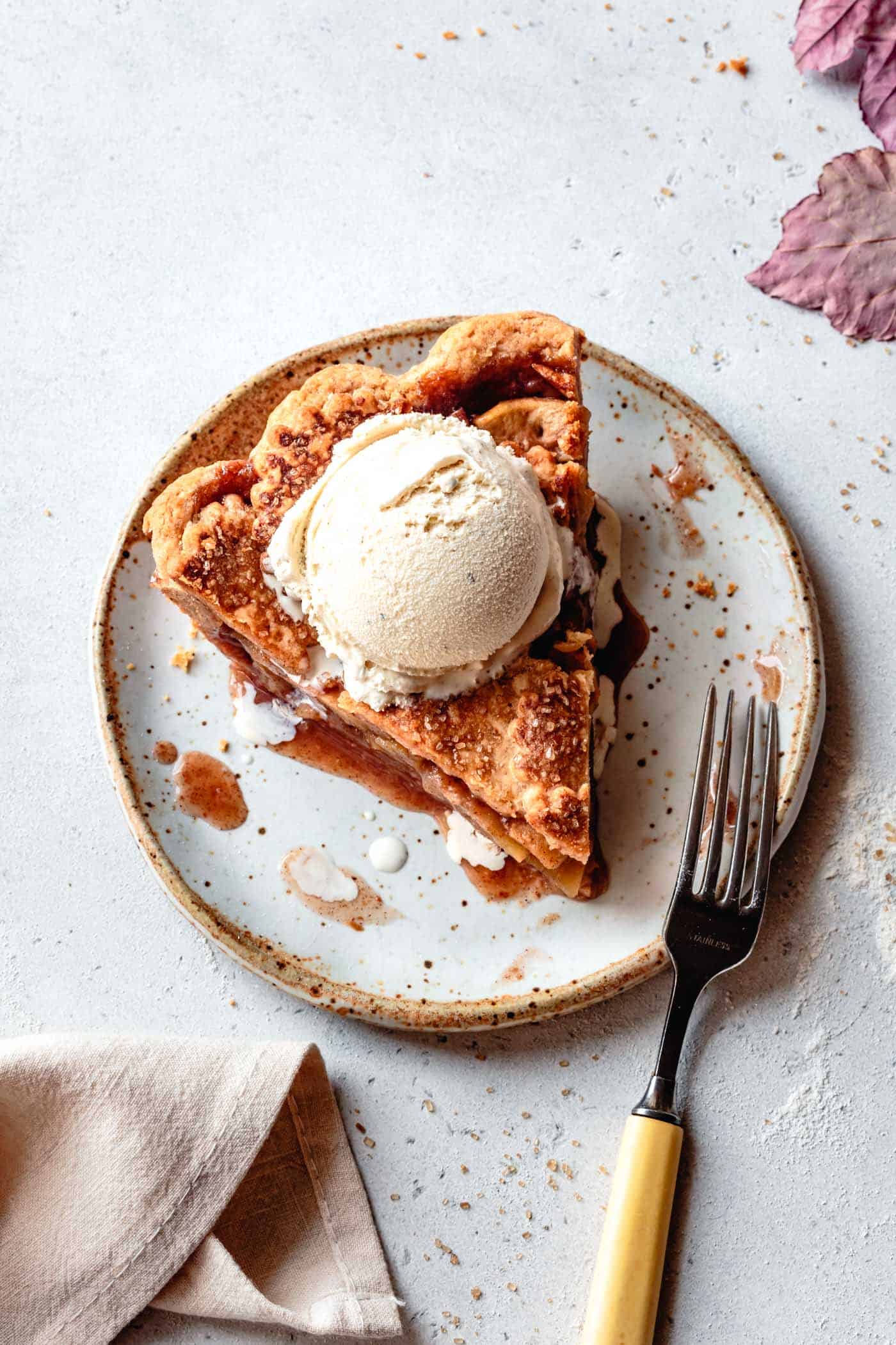 a slice of gluten-free apple pie on a plate with ice cream