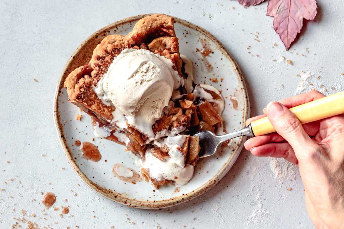 forking into a slice of gooey paleo apple pie and ice cream