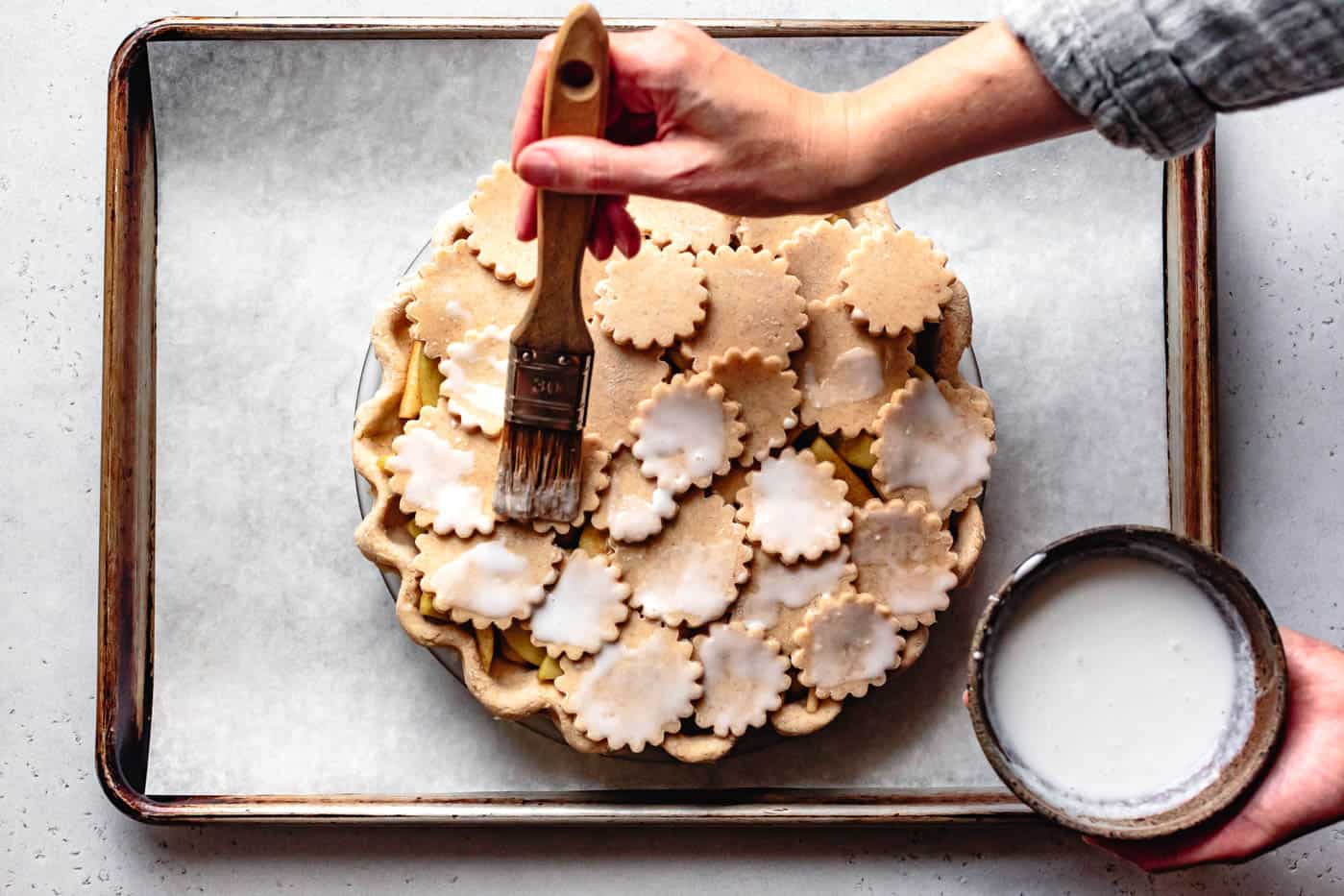 brushing gluten-free apple pie crust with coconut milk