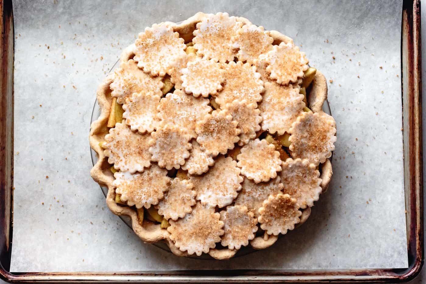 unbaked paleo apple pie topped with dough rounds and coarse sugar