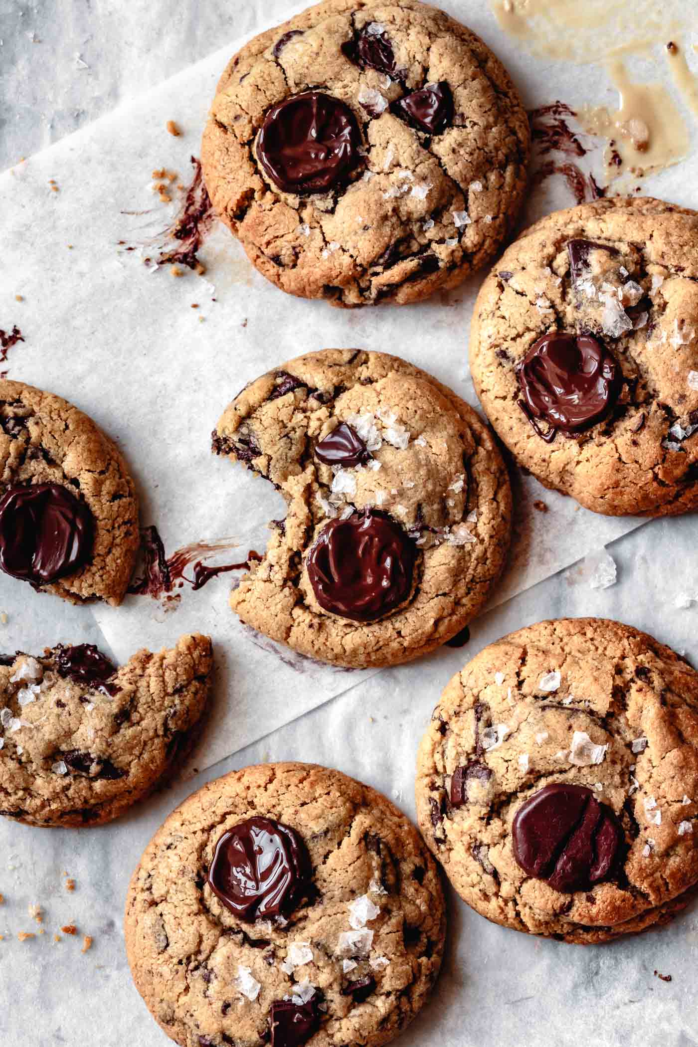 six gooey salted tahini chocolate chip cookies on parchment paper