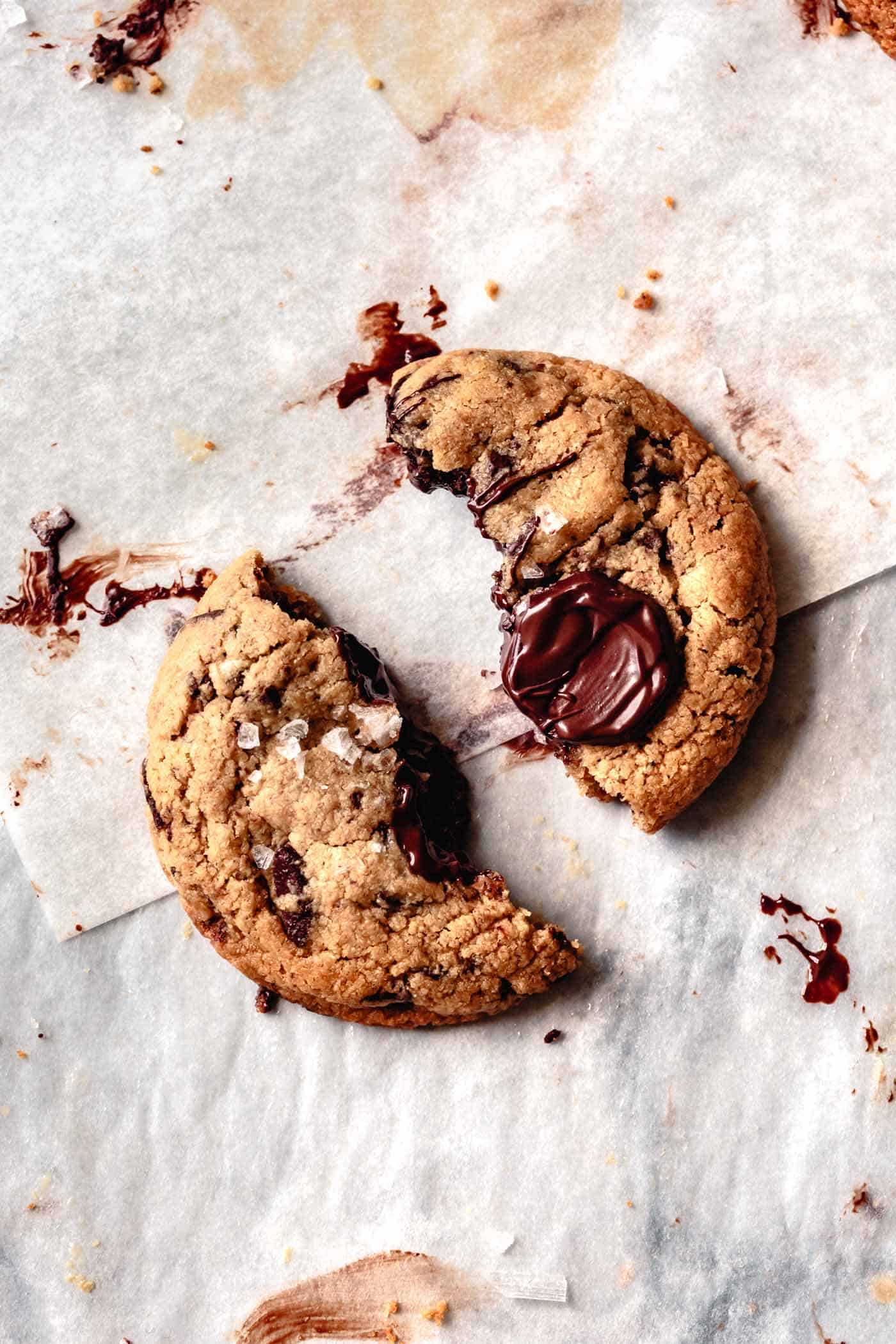 salted tahini chocolate chip cookie broken in half on parchment paper