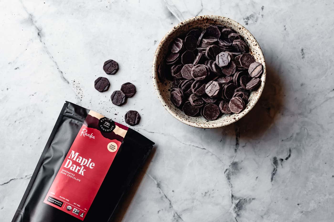 a bag and a bowl of maple dark chocolate on marble