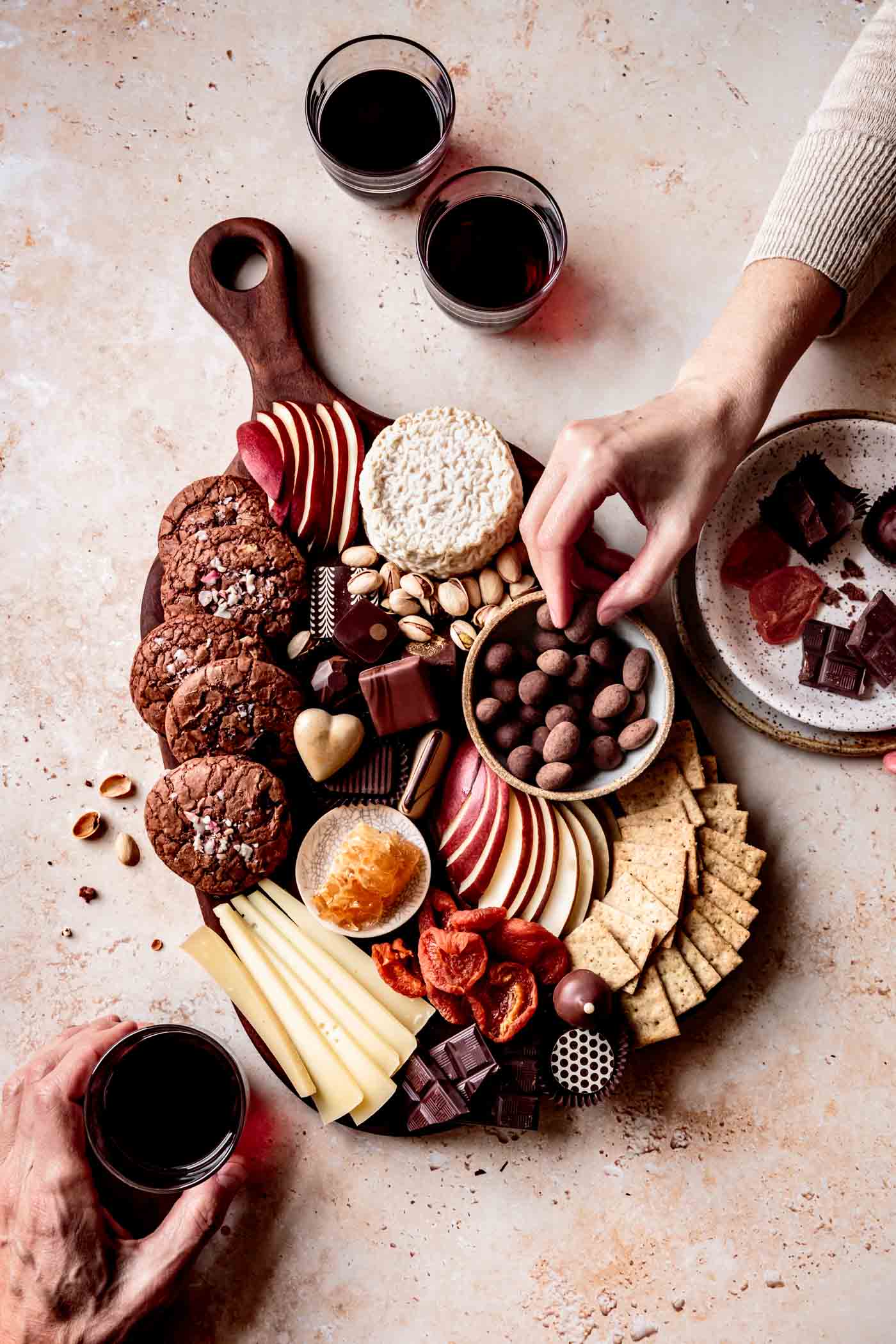 hands partaking in cheese dessert board