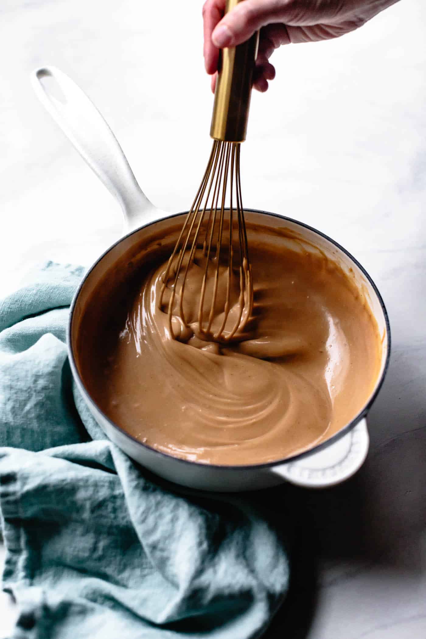 whisking creamy vegan butterscotch pudding in a pot