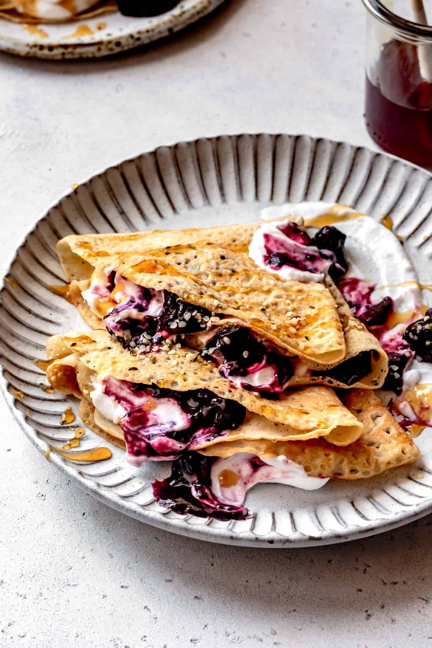 Paleo crepes on a plate with yogurt, berries, and honey