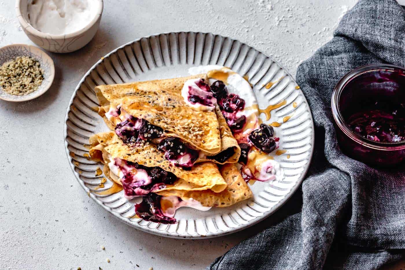 serving whole30 crepes on a plate with berries, yogurt, and honey