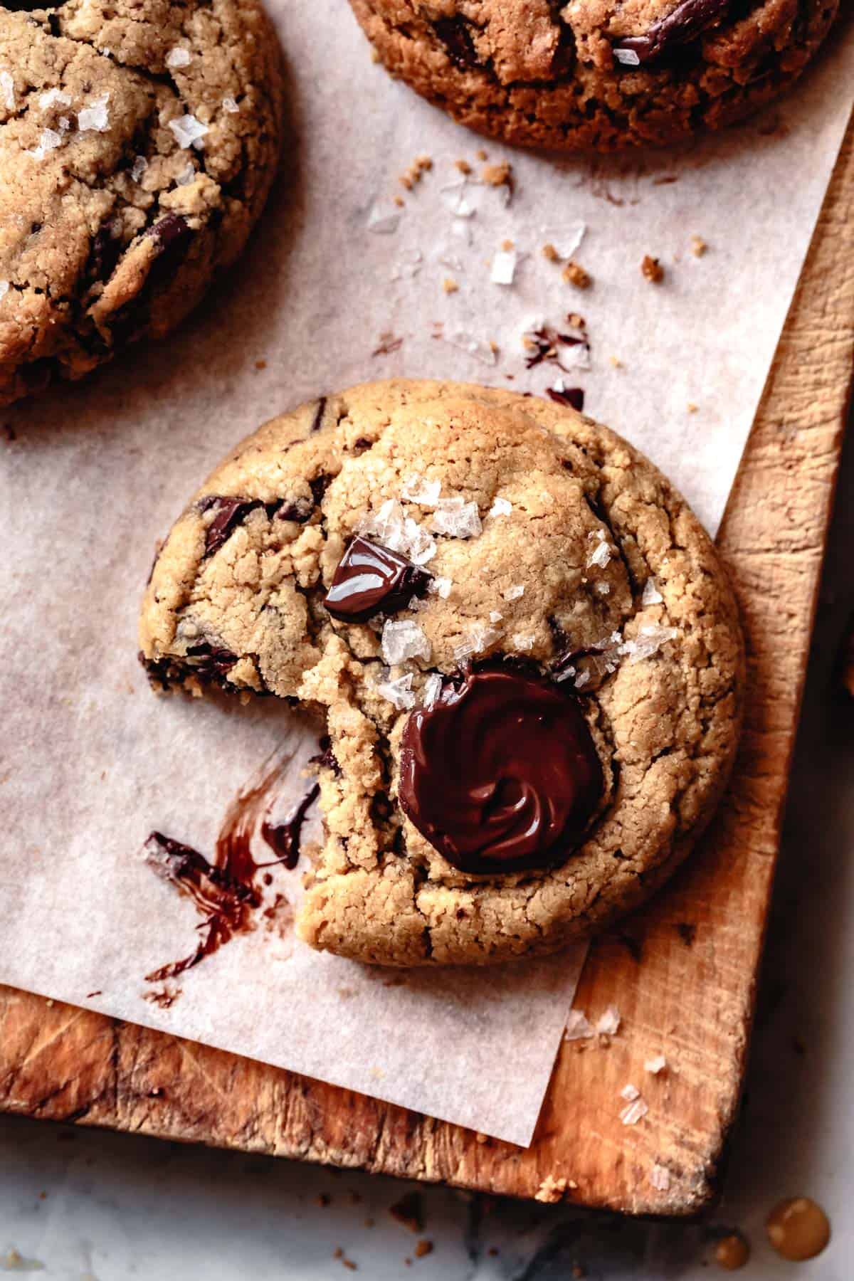 tahini chocolate chip cookie with a bite taken out parchment and wood board