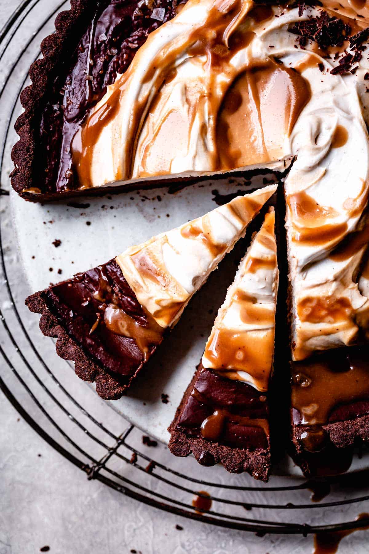 overhead of sliced chocolate tart topped with caramel and whipped cream
