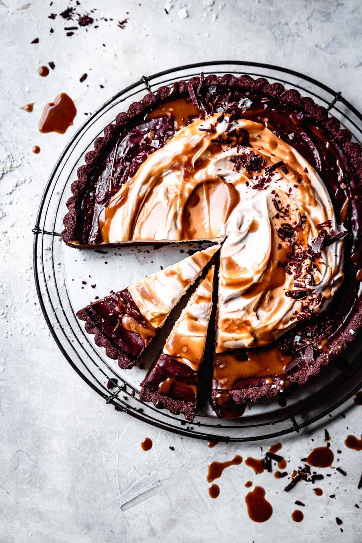 passover dessert: overhead of chocolate tart topped with caramel and whipped cream on gray plaster