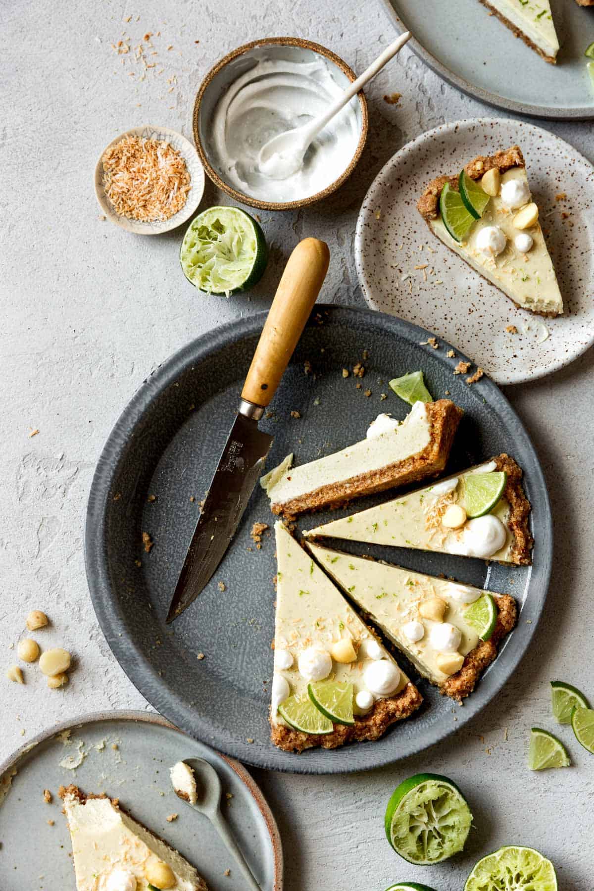 slices of coconut key lime pie in a pie plate, with plates and limes around