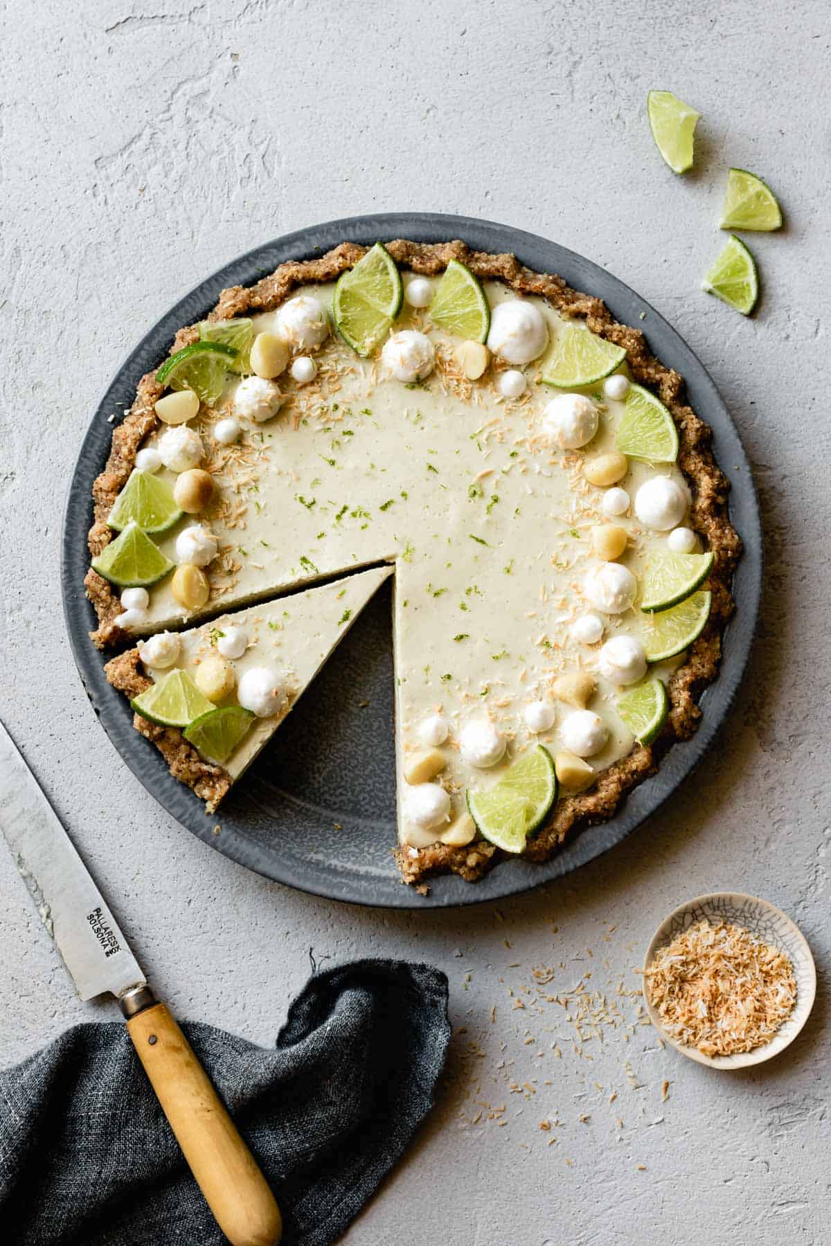 overhead of lime pie decorated with macadamia nuts and lime wedges