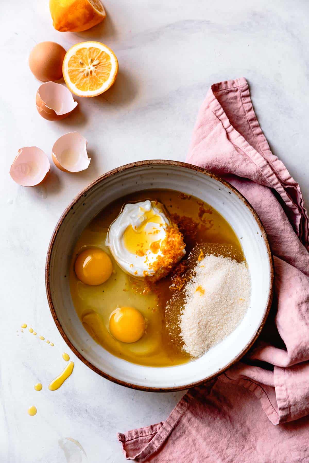 rhubarb cake ingredients: eggs, yogurt, sugar, lemon, and olive oil in a bowl
