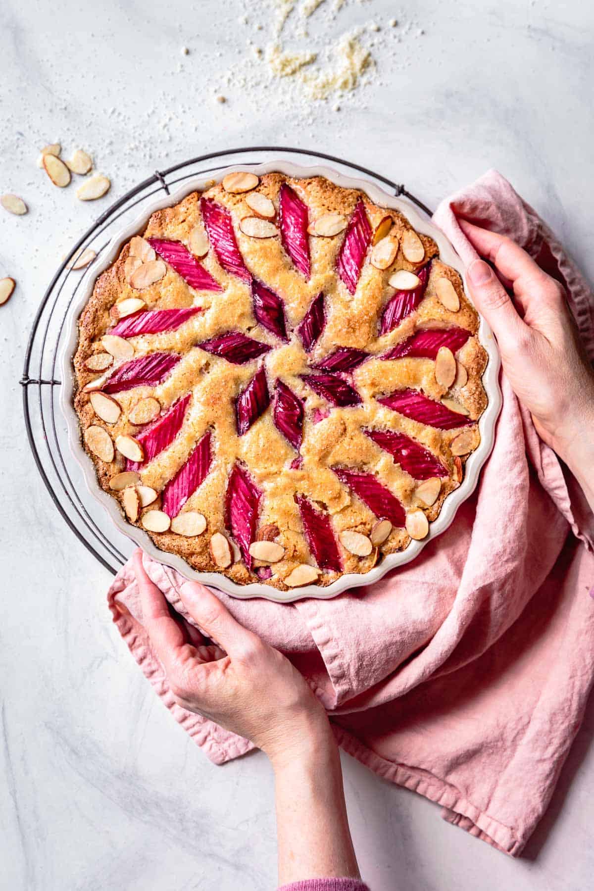 hands holding freshly baked cake with a pink linen