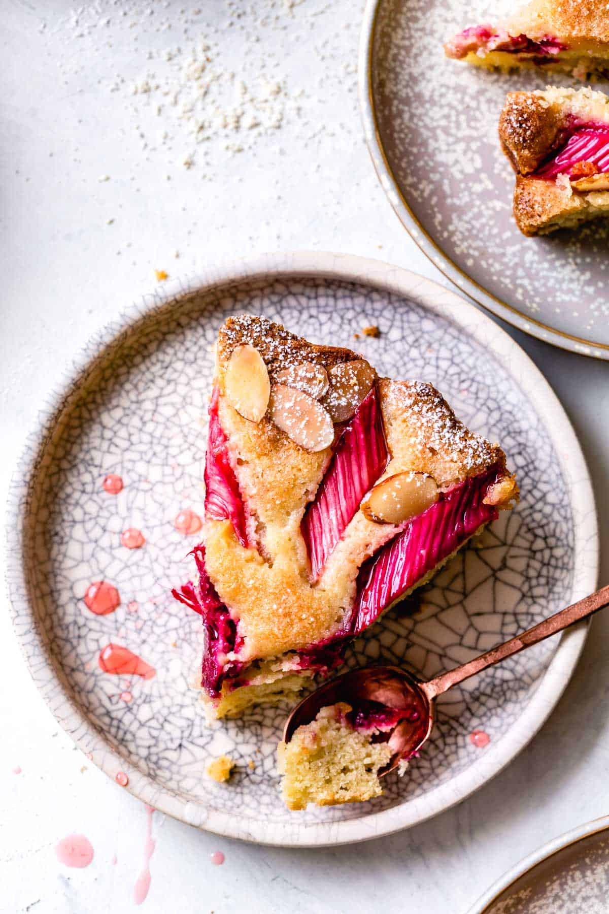 Gluten-free rhubarb cake slice on a plate with a bite taken out