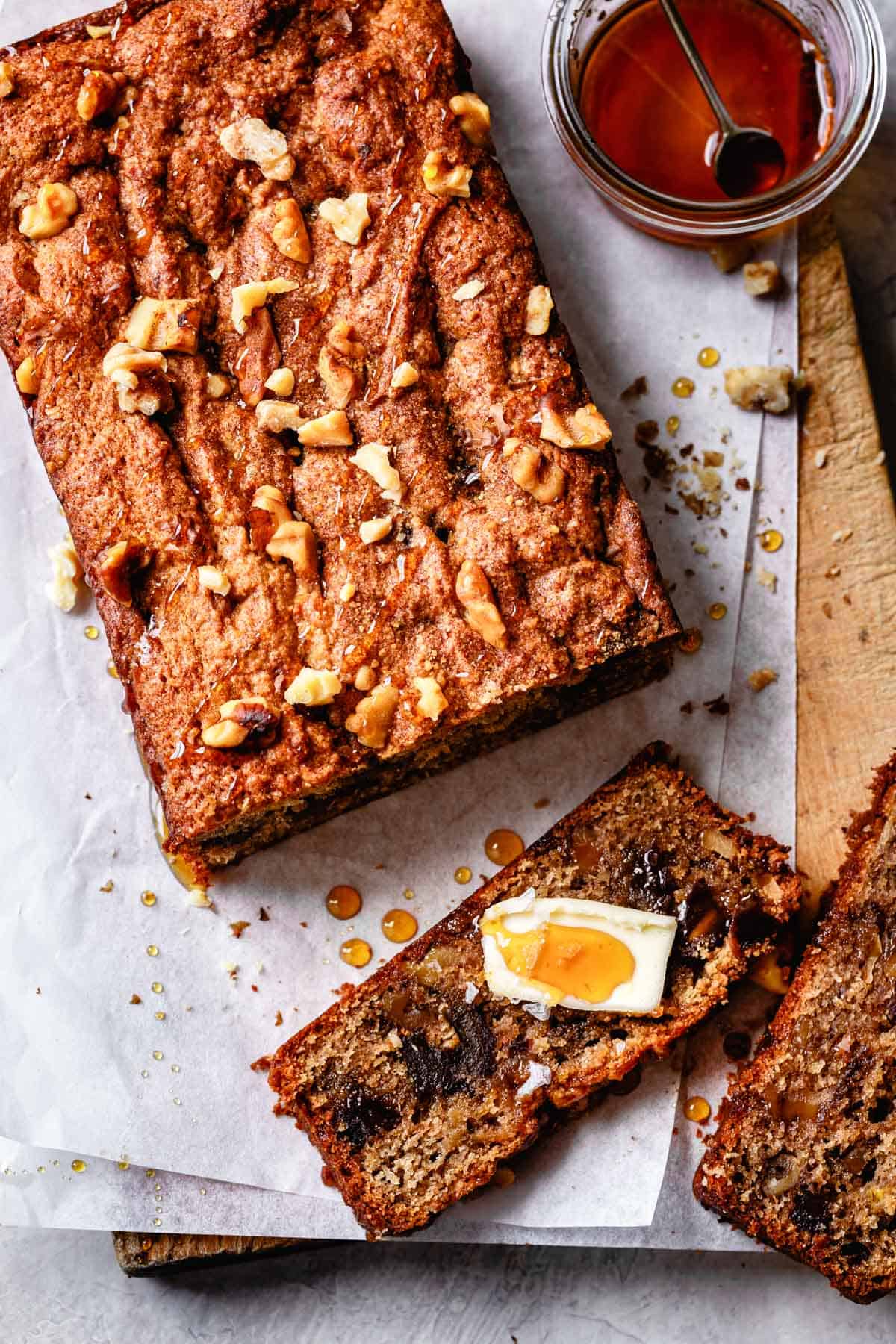 grain-free banana bread on a wooden board, sliced with butter and honey