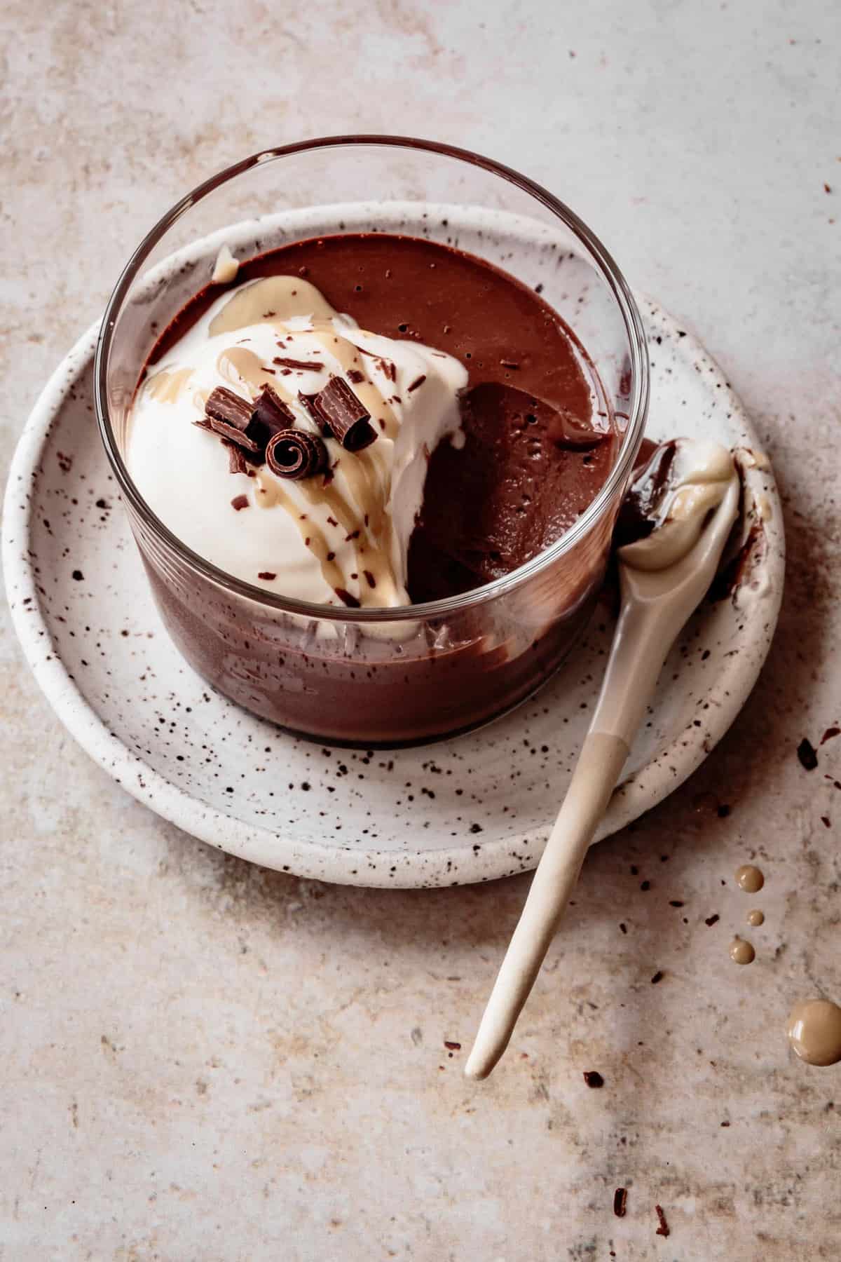 three-quarter angle of healthy chocolate pudding recipe in a glass topped with chocolate curls