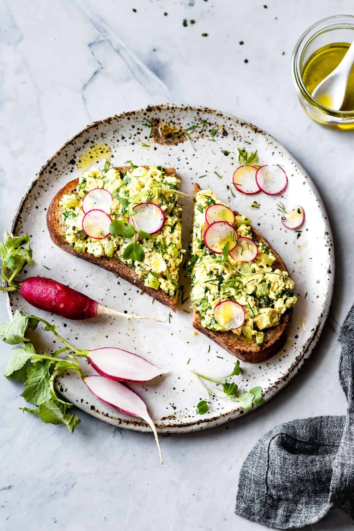 tofu egg salad recipe on toast with sliced radishes and olive oil drizzles
