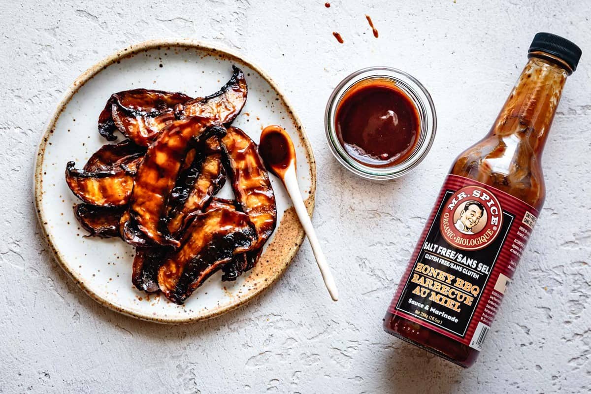 BBQ mushrooms on a plate with a bottle of BBQ sauce next to it