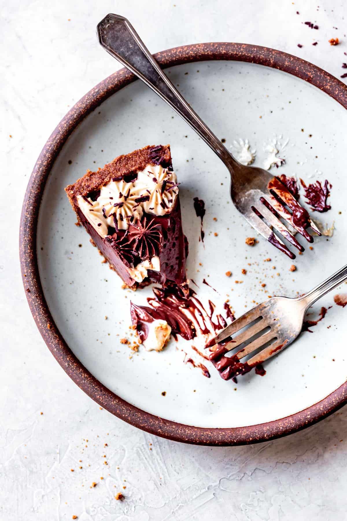 vegan chocolate pie slice on a plate, partially eaten with gooey chocolate smears on a blue plate