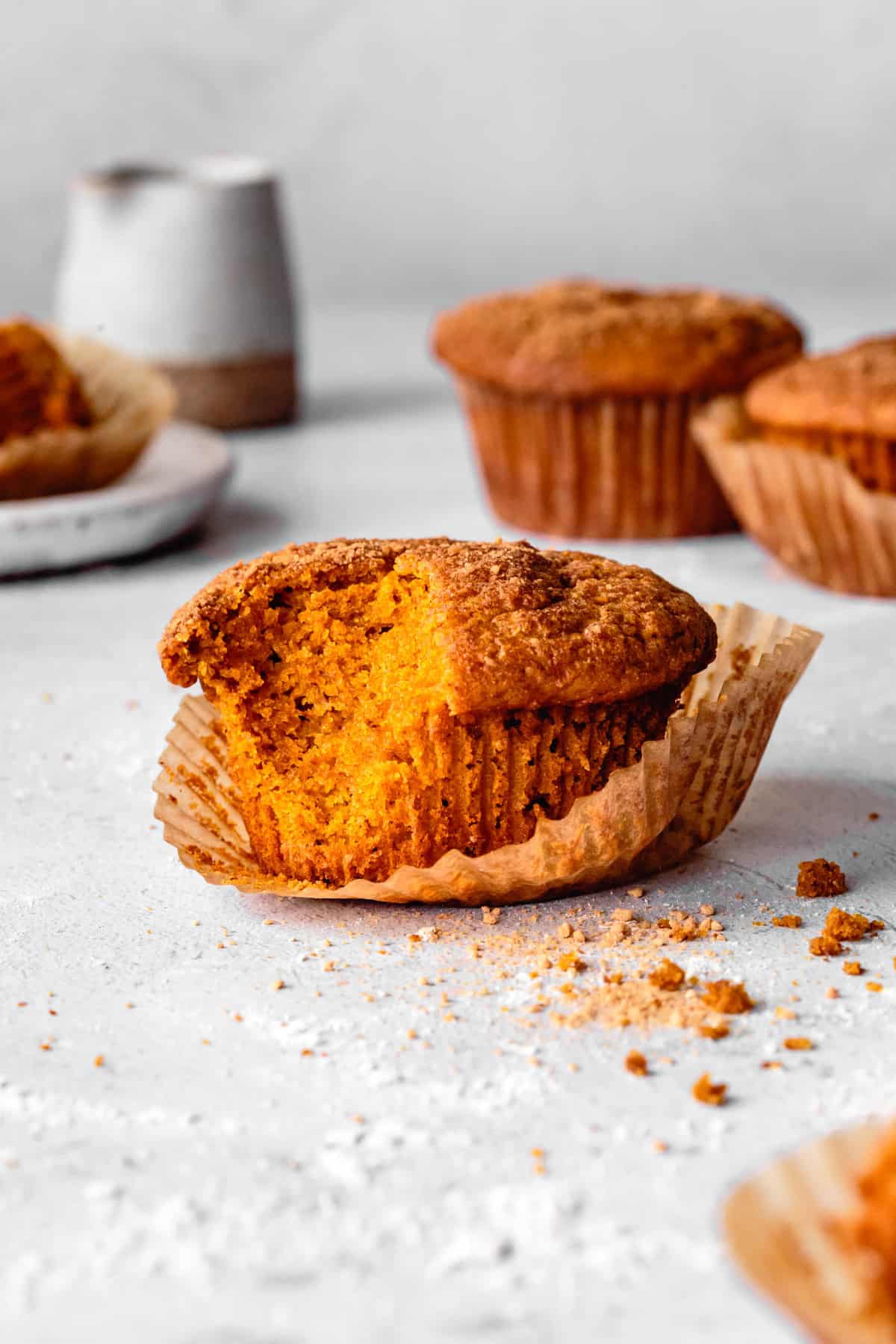 a very orange gf pumpkin muffin from the side with a bite taken out