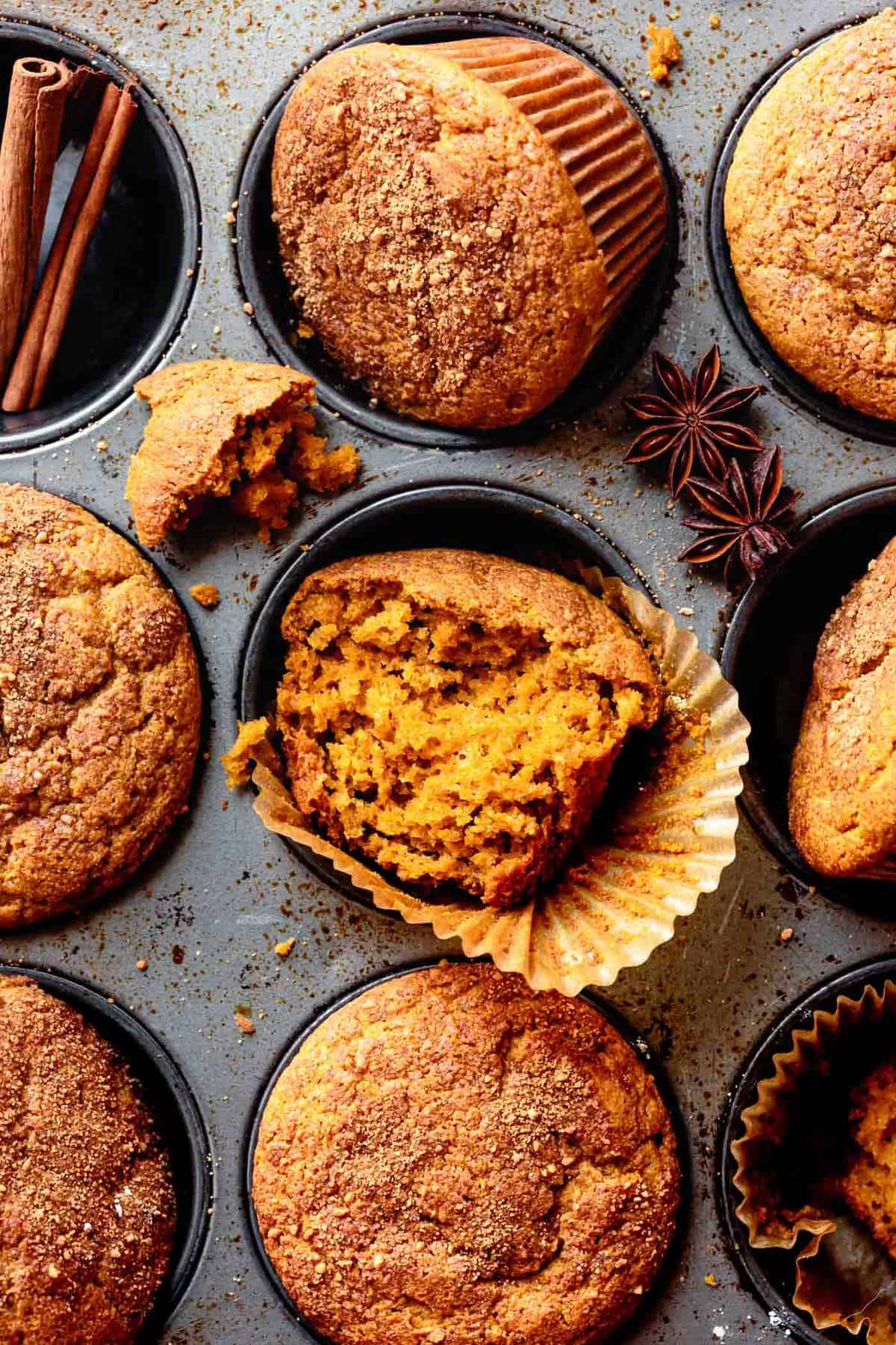 baked gluten-free pumpkin spice muffins in a tin with one broken in half