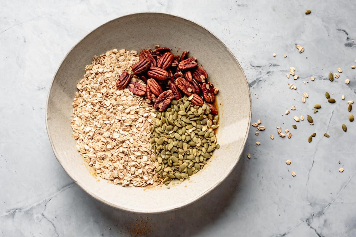 adding oats, nuts, and seeds to the bowl