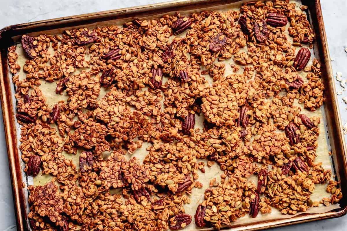 baked pumpkin seed granola broken up into clusters on a pan