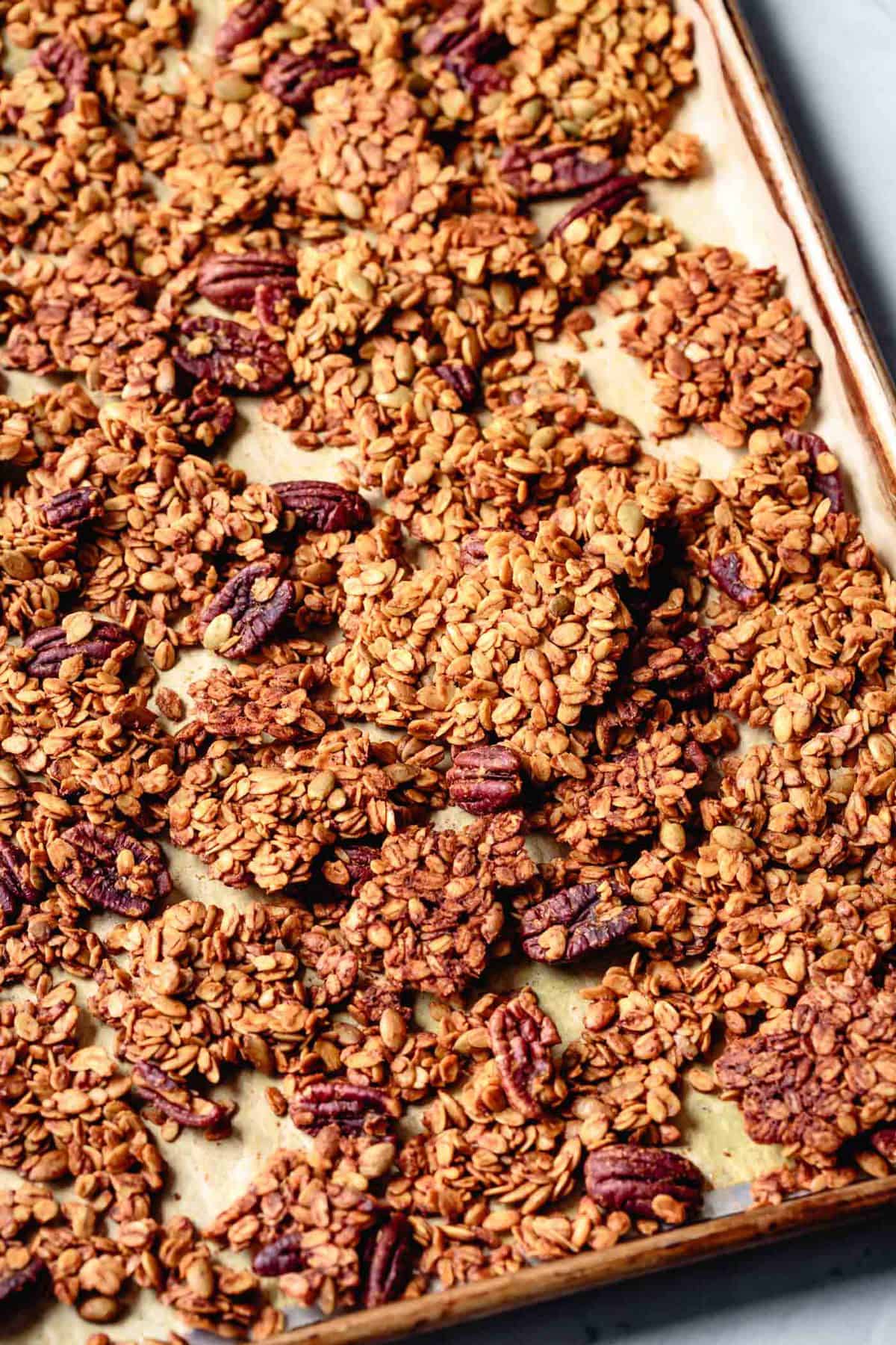 big clumps and clusters of golden pumpkin spice granola on a baking sheet