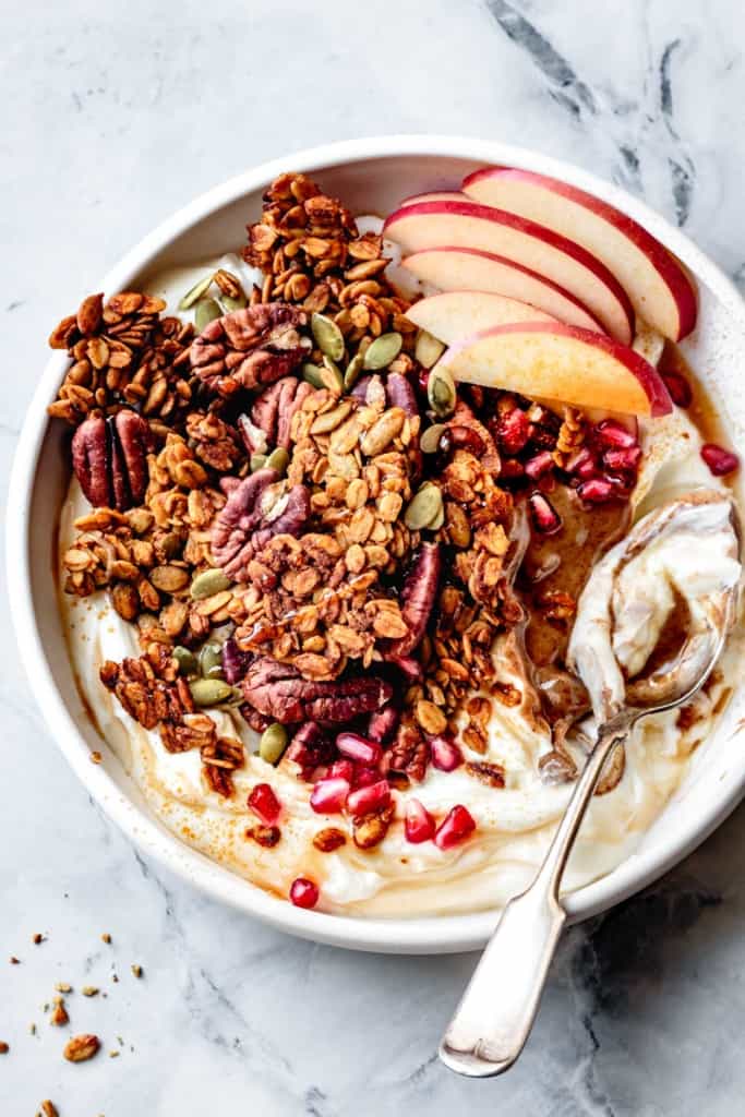 pumpkin spice granola in a bowl with yogurt, nut butter, and fruit