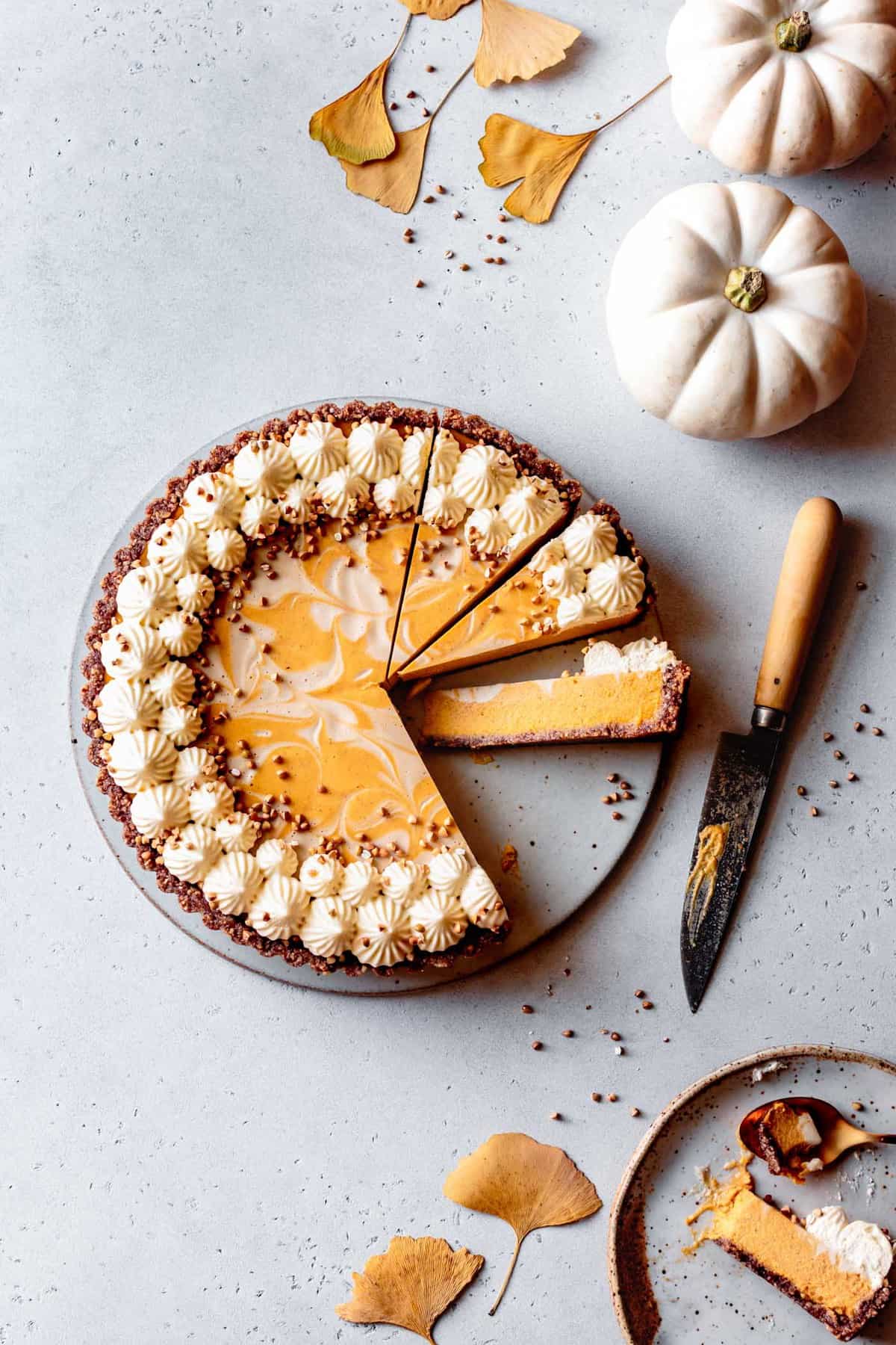 gluten-free pumpkin desserts: marbled pumpkin tart on a surface with white pumpkins and golden leaves