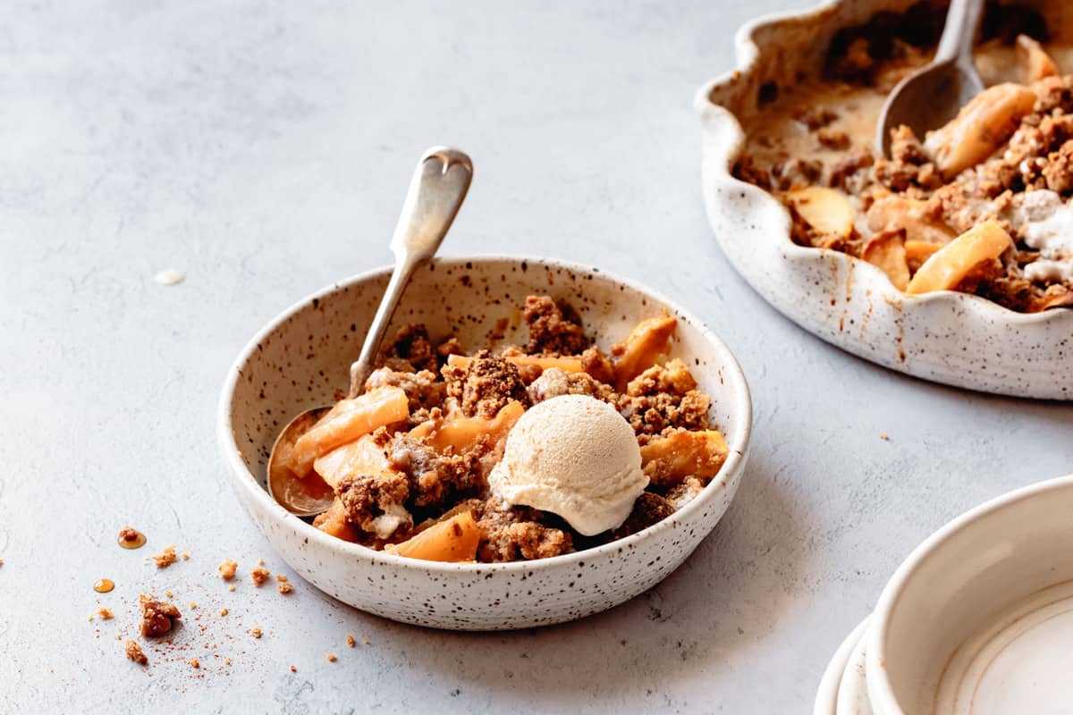 wide 3/4 angle of a bowl of healthy apple crisp topped with ice cream