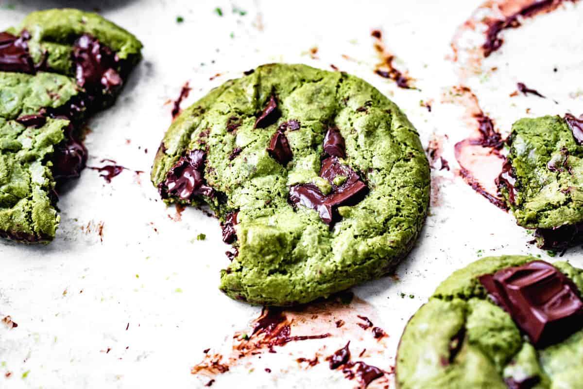 wide crop of matcha chocolate chip cookie on a white surface with a bite taken out