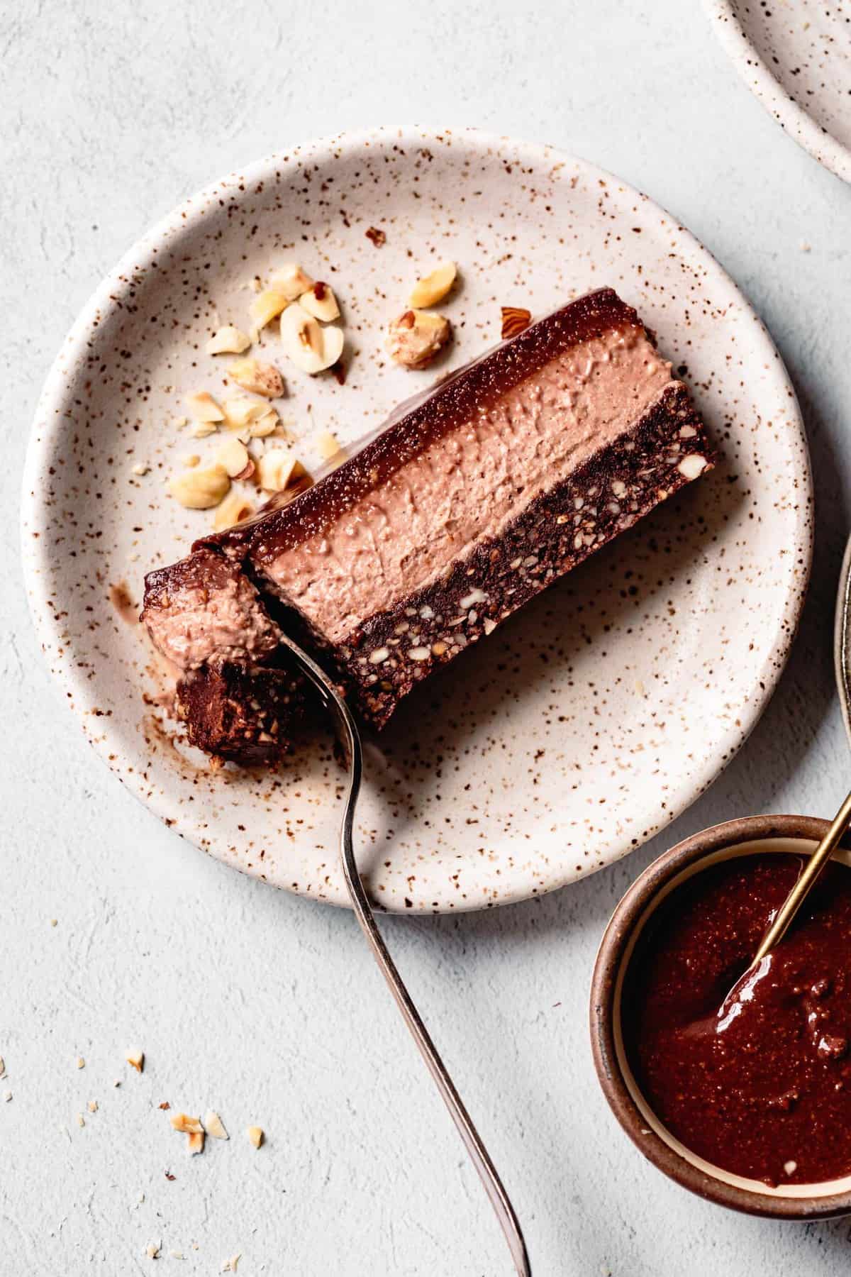 slice of no-bake chocolate hazelnut cheesecake on a plate with fork cutting off a piece