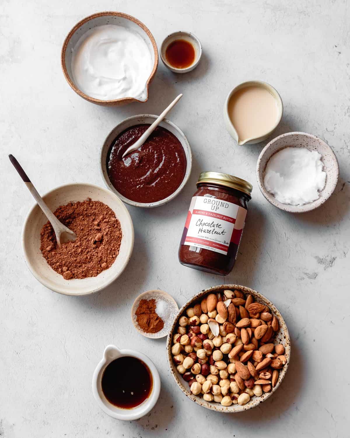 ingredients for no-bake nutella cheesecake arranged in pretty bowls on a stone surface