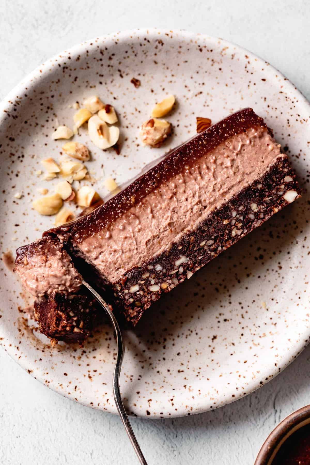 close-up of chocolate hazelnut cheesecake slice on a speckled plate being forked