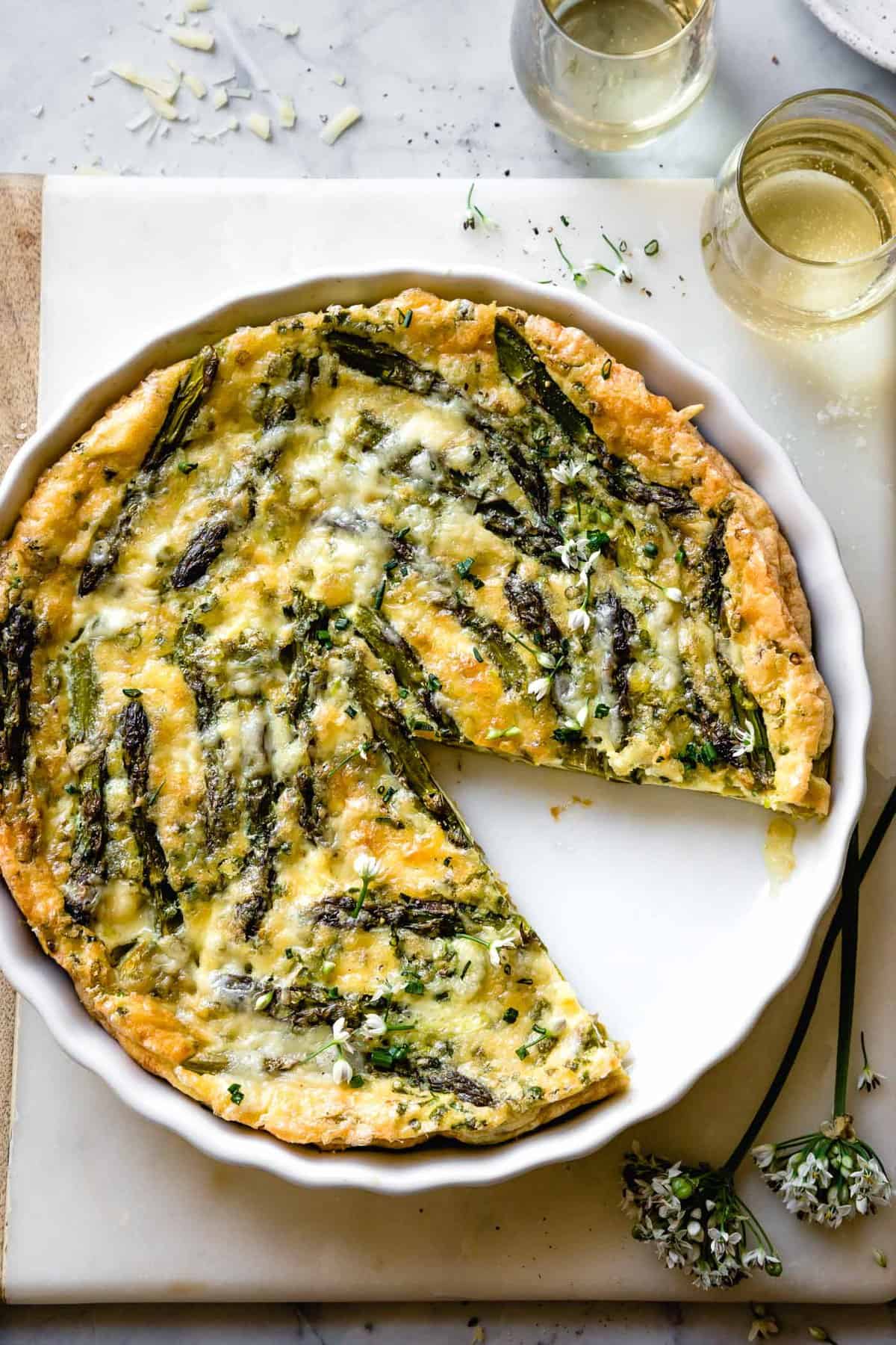 close up of asparagus crustless quiche with chive blossoms and gooey cheese on top