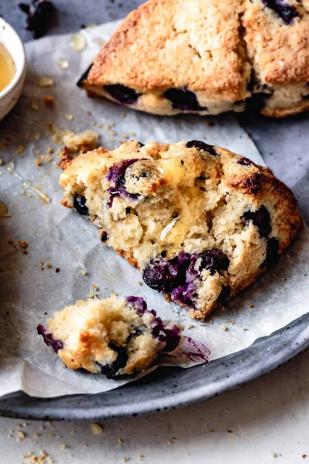 closeup of a broken berry scone showing the floofy, craggy crumb with gooey honey on top