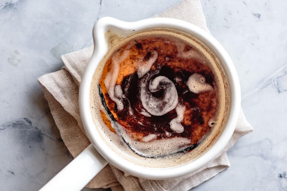 golden brown butter with swirls of foam in a white pot