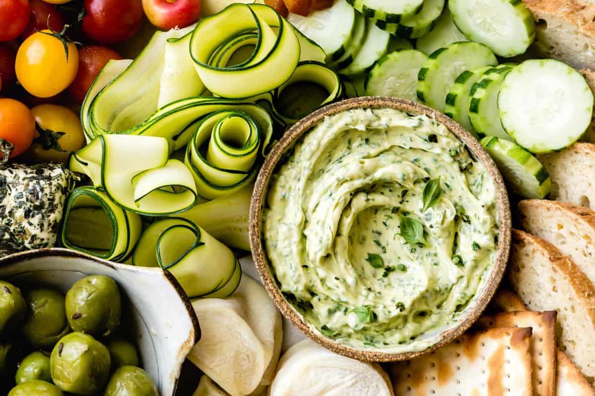 close-up of basil butter swirled in a bowl on a veggie and cheese platter