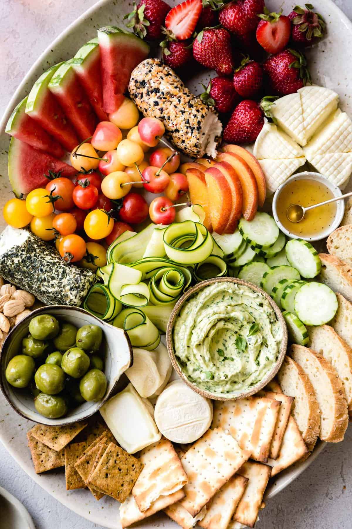 A colorful cheeseboard with a bowl of basil butter swirled prettily in the center