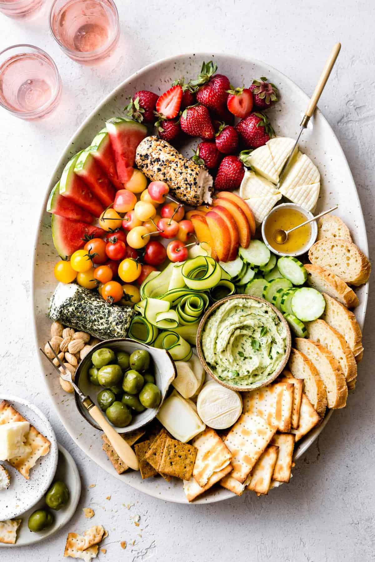 oval platter loaded with a rainbow of vibrant summer fruits and vegetables, cheeses, bread, and crackers